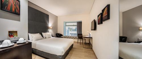 a hotel room with a bed and a desk at Benjamin Business Hotel in Herzelia 