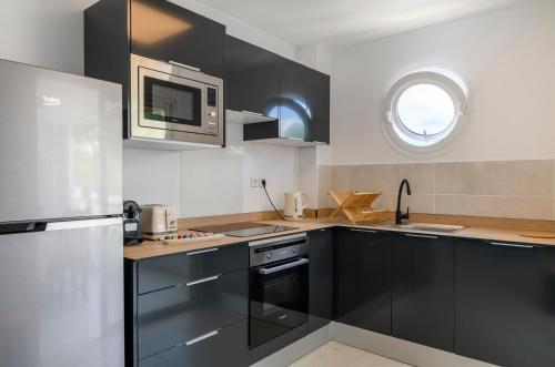 a kitchen with black cabinets and a microwave at MadouBamboo in Ducos