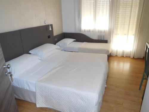 2 camas en una habitación de hotel con sábanas blancas en Hotel Emperador en Lido di Jesolo