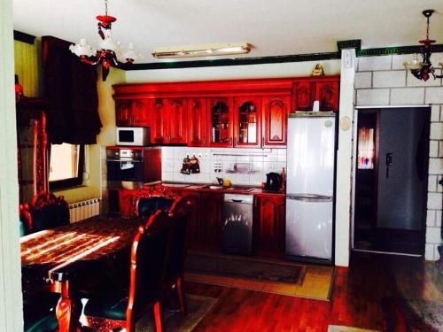 a kitchen with red cabinets and a table and a refrigerator at Debar Maalo Apartment in Skopje
