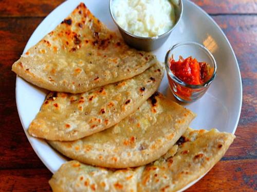 a white plate with five tortillas and a bowl of sauce at Hotel Nova Vesu in Surat