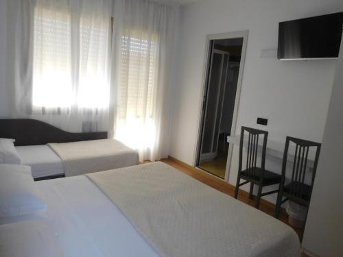 a hotel room with two beds and a chair at Hotel Emperador in Lido di Jesolo