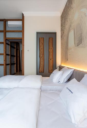 two beds in a room with white sheets at Villa Boutique Hotel in Mukacheve