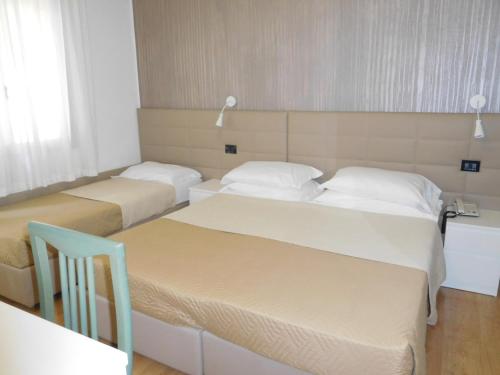 a room with two beds and a chair in it at Hotel Emperador in Lido di Jesolo