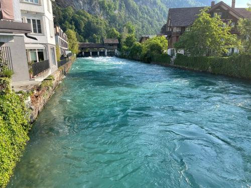 a river with turquoise water next to some buildings at Aparthotel Krone - Self Check-In in Interlaken
