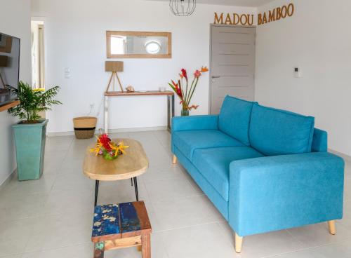 a living room with a blue couch and a table at MadouBamboo in Ducos