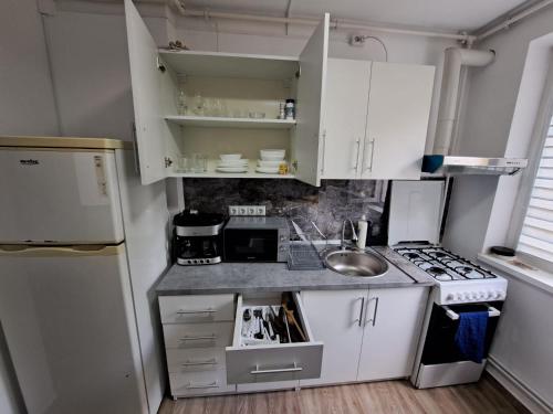 una pequeña cocina con armarios blancos y fregadero en Apartament 2 camere en Zalău