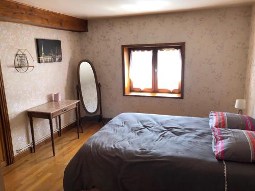 a bedroom with a bed and a table and a window at Gîte de la Croix Mandet 