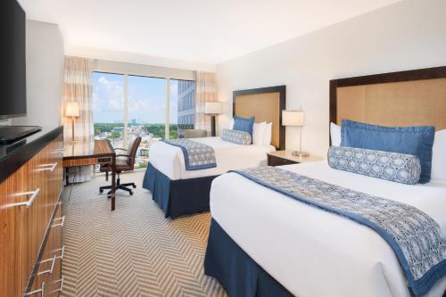 a hotel room with two beds and a desk and a television at The Westshore Grand, A Tribute Portfolio Hotel, Tampa in Tampa