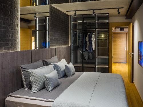 una camera da letto con un grande letto bianco con cuscini di PAUZA apartman a Novi Sad