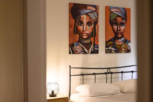 a bedroom with three paintings of women on the wall at Seaduced Beachfront Villa by CorfuEscapes in Glyfada