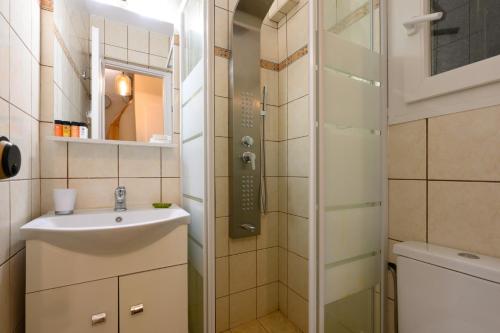 a small bathroom with a sink and a shower at Seaduced Beachfront Villa by CorfuEscapes in Glyfada