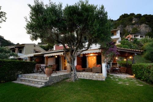 a house with a tree in the yard at Seaduced Beachfront Villa by CorfuEscapes in Glyfada