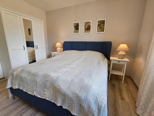 um quarto com uma cama azul e duas mesas com candeeiros em Ferienwohnung Bergblick - a66742 em Bad Sachsa