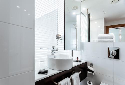 a white bathroom with a sink and a mirror at Benjamin Business Hotel in Herzelia 