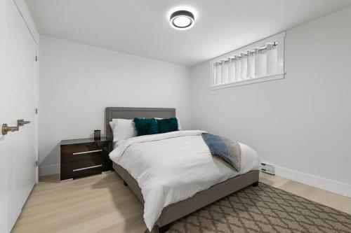 a white bedroom with a bed and a night stand at Beautiful 1 bedroom apartment - private entrance in Moncton