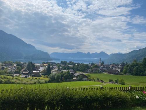 a town in a green field with mountains in the background at Garten Apartment Diwoky in Sankt Gilgen