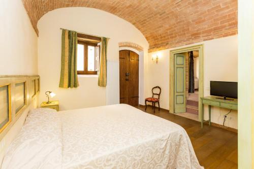 a bedroom with a white bed and a television at Borgo Colognola - Dimora Storica in Cenerente