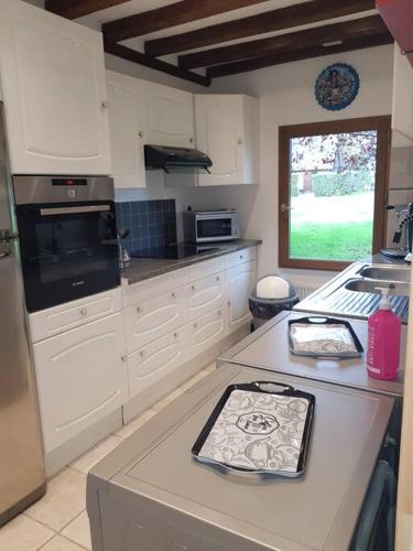 une cuisine avec des armoires blanches et un comptoir dans l'établissement Maison du domaine de la petitière, à Bonneville-la-Louvet