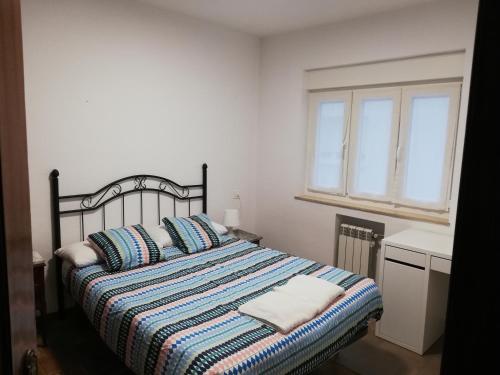 1 dormitorio con 1 cama con manta a rayas y ventana en Apartamento Dominicos, en Oviedo