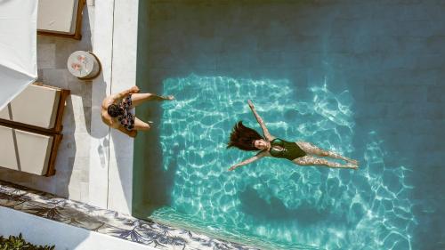 two people swimming in the water at a swimming pool at Hara Suites in Parga