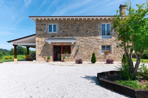 a stone house with a driveway in front of it at Villa Colasa, casa rústica con encanto en Selaya in Selaya