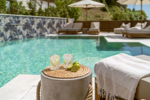 a pool with a table with two glasses and some chairs at Hara Suites in Parga