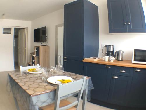 cocina con armarios azules, mesa y sillas en Les studios de Philibert, en Figeac