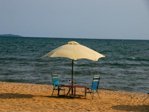a table and two chairs under an umbrella on the beach at Kep Villa Hill Guest House 1 in Kep