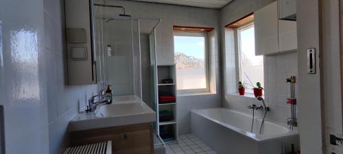 een badkamer met 2 wastafels, een bad en een raam bij Ecolodge Tilburg Directors room and Swimmingpool in Tilburg