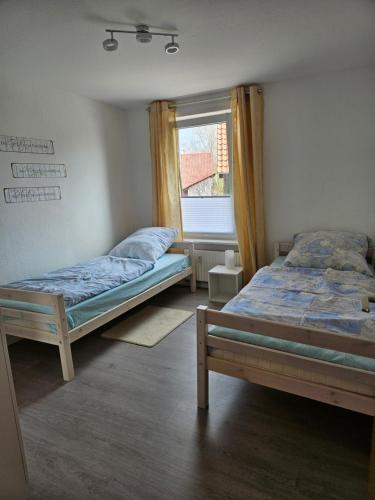 dwa łóżka w pokoju z oknem w obiekcie Ferienwohnung - Stern - w mieście Rollshausen