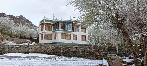 a large house on a stone wall in the snow at Tsabgyat Homestay in Leh