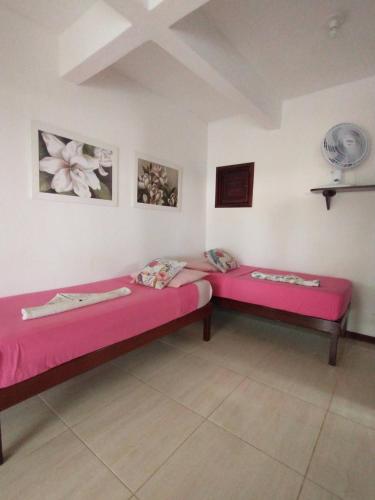 two beds in a room with pink sheets at Vila Beija-flor in Canoa Quebrada