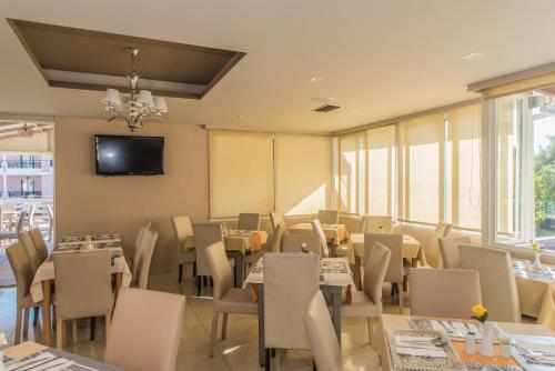 a restaurant with tables and chairs and a tv on the wall at Porto Planos Beach Hotel in Tsilivi