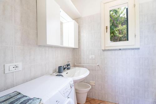 een badkamer met een wastafel, een toilet en een raam bij Villetta Sant'Andrea - Goelba in SantʼAndrea