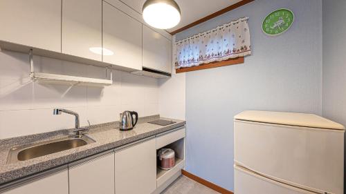 uma pequena cozinha com armários brancos e um lavatório em Eungabi Pension em Gangneung