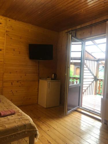 a bedroom with a flat screen tv on a wooden wall at Садиба "ЯНА" in Slavske