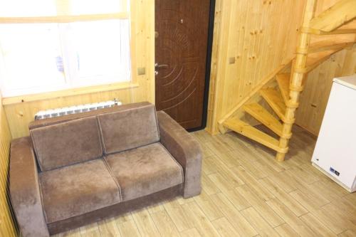 a living room with a brown couch and a staircase at Садиба У Романа 'двохрівневий номер' in Verkhneye Sinevidnoye