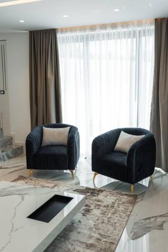 a living room with two chairs and a table at Palmera Prive Vila in Sarandë