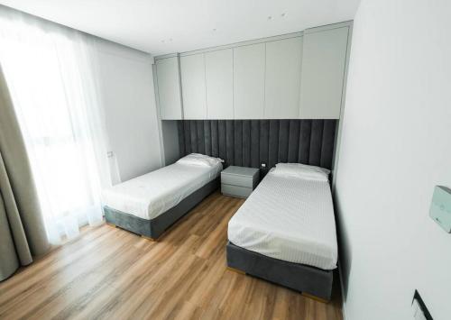 two beds in a room with wood floors at Palmera Prive Vila in Sarandë