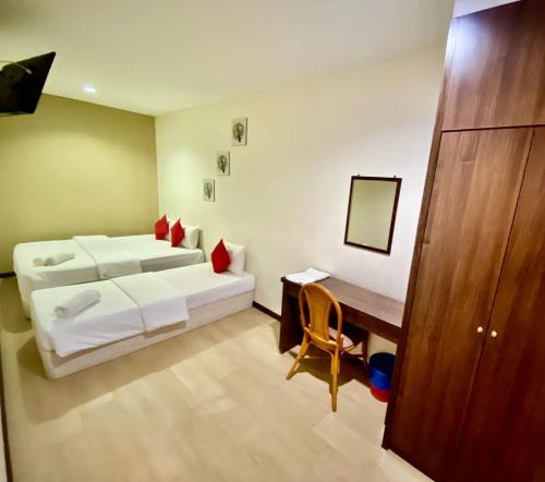 a bedroom with two beds and a desk and a table at Rimaniz Hotel Alor Setar in Alor Setar