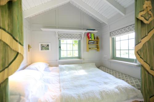 a small bedroom with a bed and two windows at Cottage Orné in Long Bredy