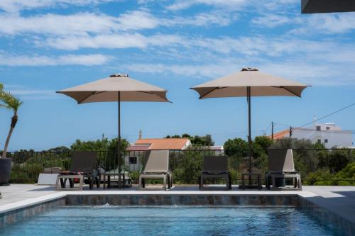 a pool with umbrellas and chairs next to a swimming pool at Ria Formosa Guest House in Faro