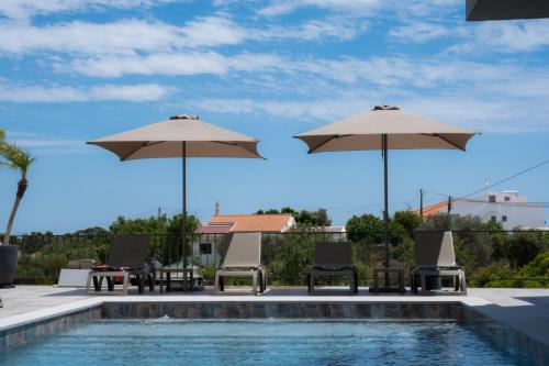 een zwembad met parasols en stoelen naast een zwembad bij Ria Formosa Guest House in Faro