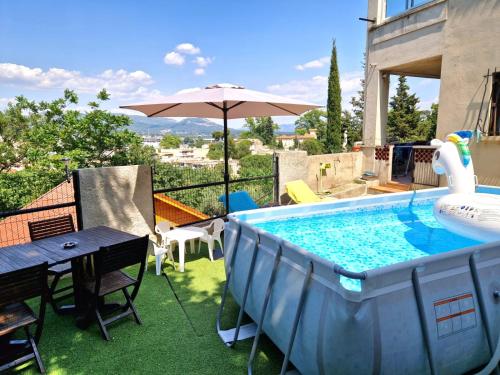 une piscine avec une table et un parasol dans l'établissement Villa Marseille dans les hauteurs, à Marseille
