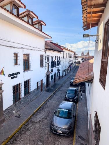 two cars parked on a street next to buildings at Hotel Cusco Plaza Saphi in Cusco