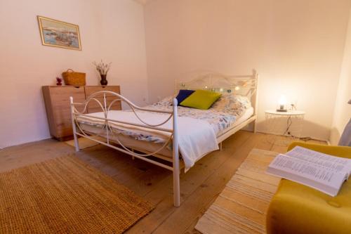 1 dormitorio con 1 cama blanca y 1 silla amarilla en Authentic stone house Rustica near Makarska Riviera en Lovreć