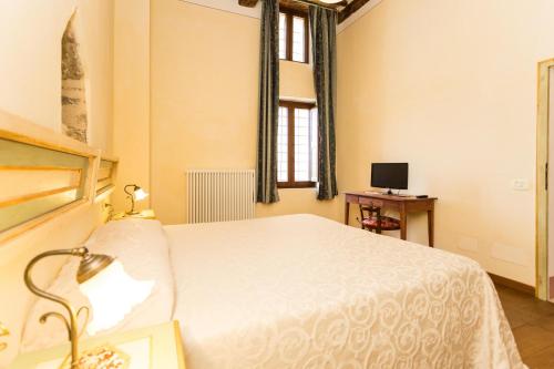 a bedroom with a white bed and a desk with a computer at Borgo Colognola - Dimora Storica in Cenerente