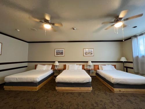 two beds in a room with two ceiling fans at Wells Gray Inn in Clearwater