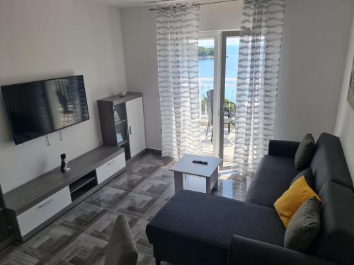 a living room with a couch and a tv at Apartments Pavlić in Saplunara